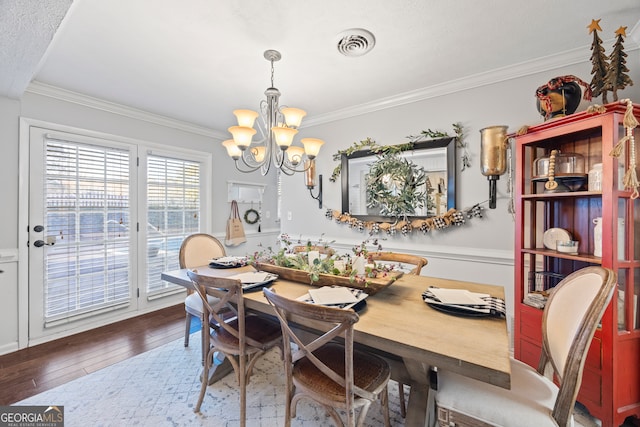 dining area with crown molding, hardwood / wood-style floors, a textured ceiling, and an inviting chandelier