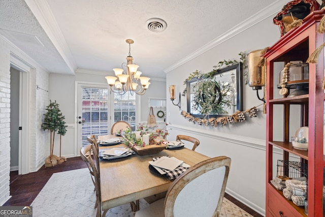 dining area with ornamental molding, dark wood-type flooring, a textured ceiling, and a notable chandelier