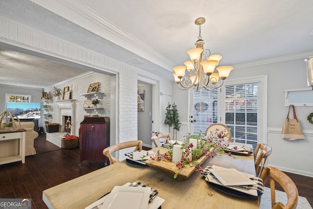 dining room with a fireplace, dark hardwood / wood-style flooring, ornamental molding, and a notable chandelier