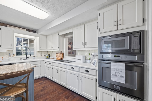 kitchen featuring oven, white cabinetry, sink, and tasteful backsplash