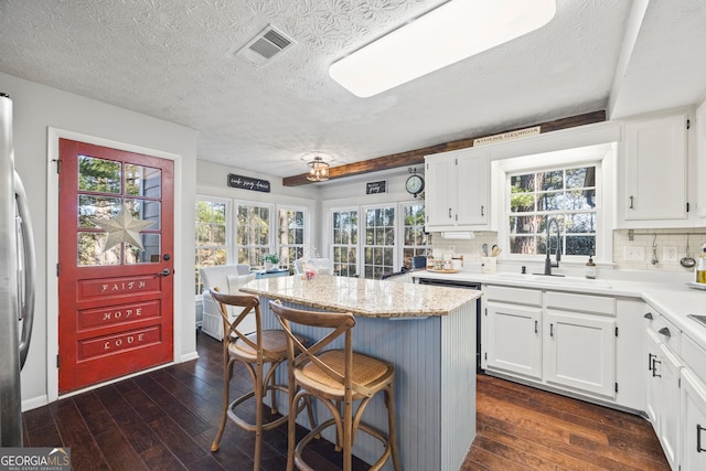 kitchen featuring tasteful backsplash, white cabinetry, a breakfast bar, and sink