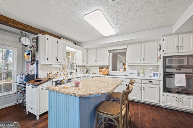 kitchen with wall oven, a center island, white cabinetry, and sink