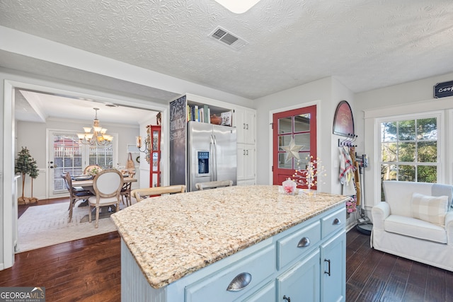 kitchen with dark wood-type flooring, blue cabinetry, decorative light fixtures, stainless steel fridge with ice dispenser, and a center island