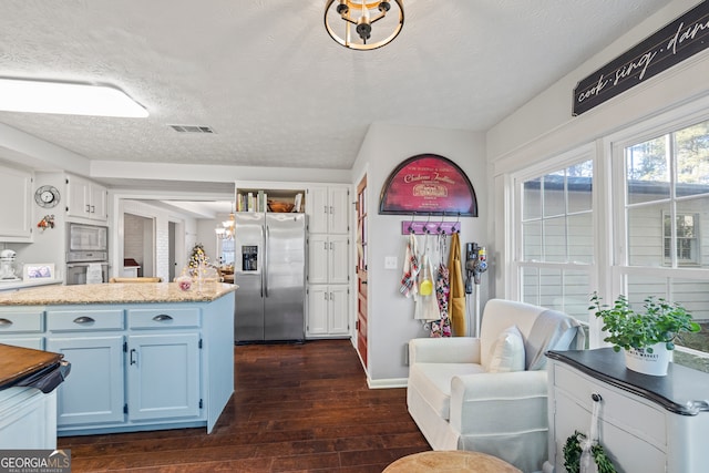 kitchen with light stone counters, dark hardwood / wood-style floors, a textured ceiling, white cabinets, and appliances with stainless steel finishes