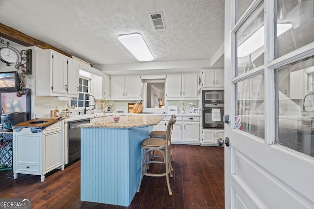 kitchen with wall oven, a center island, built in microwave, white cabinets, and black dishwasher