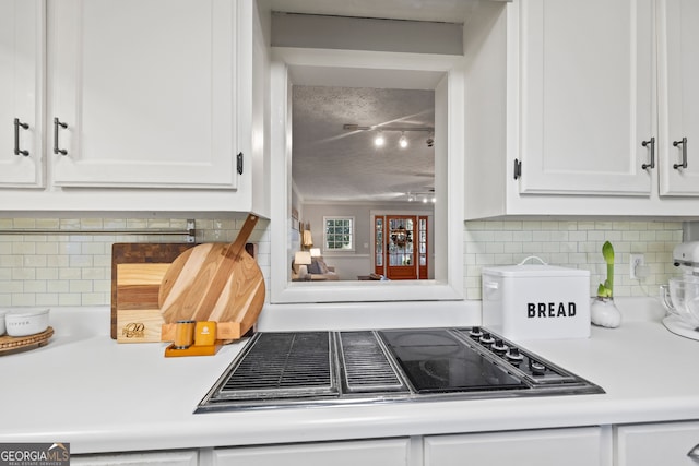 kitchen featuring white cabinets, a textured ceiling, tasteful backsplash, and gas stovetop