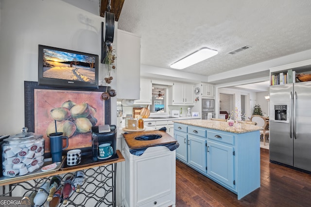 kitchen featuring a textured ceiling, stainless steel appliances, blue cabinets, a center island, and dark hardwood / wood-style floors