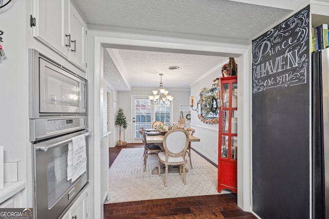 dining room featuring a notable chandelier, dark hardwood / wood-style flooring, ornamental molding, and a textured ceiling