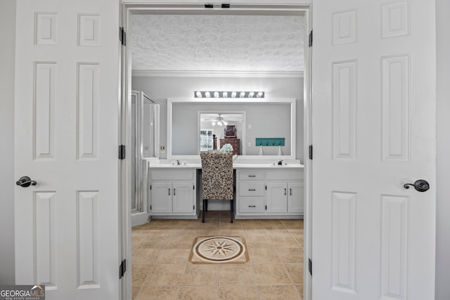 bathroom featuring ceiling fan, a textured ceiling, a shower with door, vanity, and ornamental molding