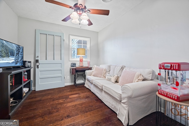 living room with a textured ceiling, ceiling fan, and dark wood-type flooring