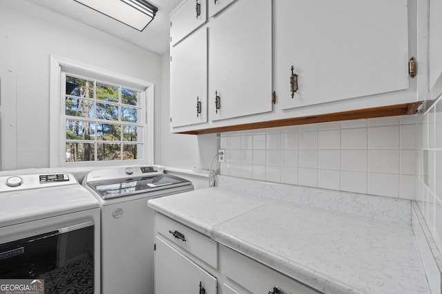 washroom with washer and dryer and cabinets