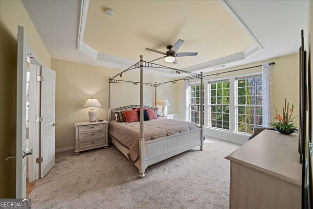 carpeted bedroom with ceiling fan and a raised ceiling