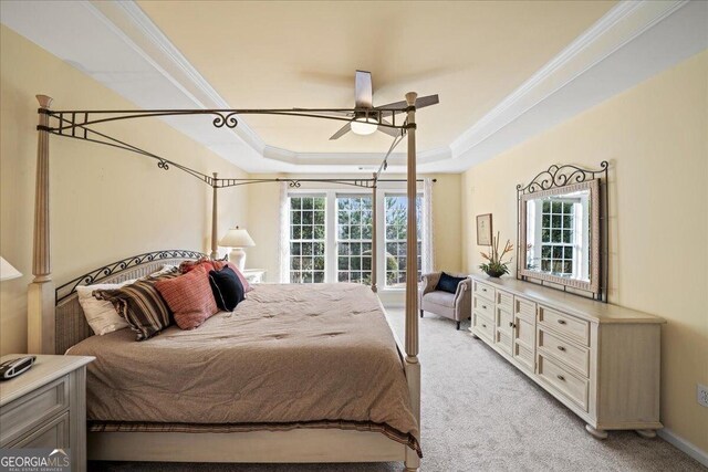 carpeted bedroom with a raised ceiling, ceiling fan, and ornamental molding