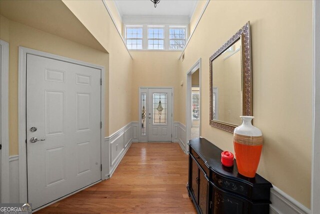 doorway to outside with plenty of natural light, ornamental molding, and light hardwood / wood-style flooring