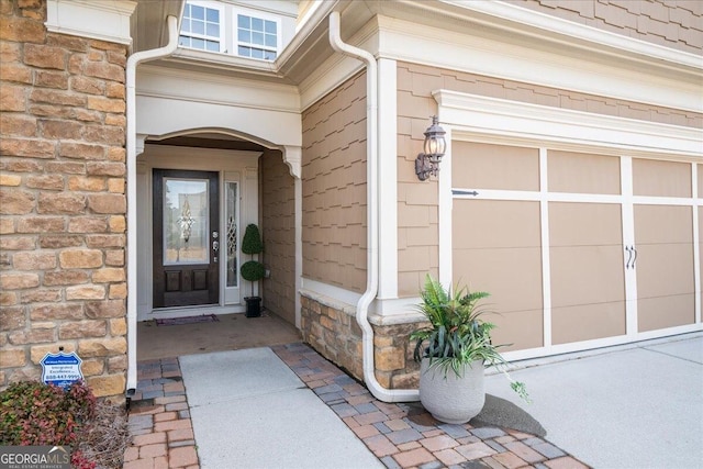 doorway to property featuring stone siding and an attached garage