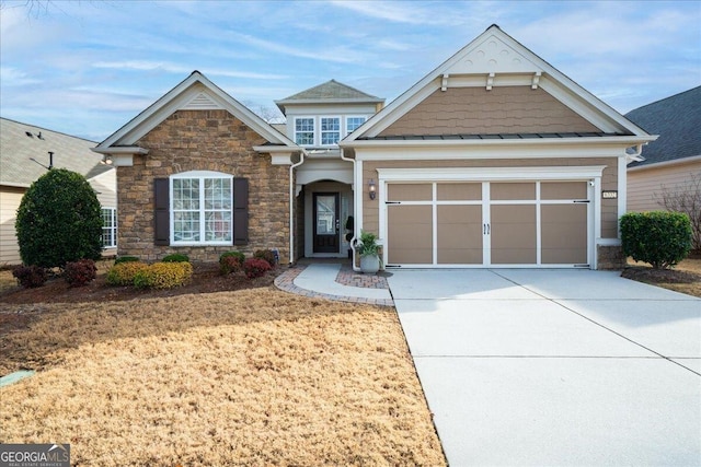 view of front of home with a garage, driveway, and stone siding