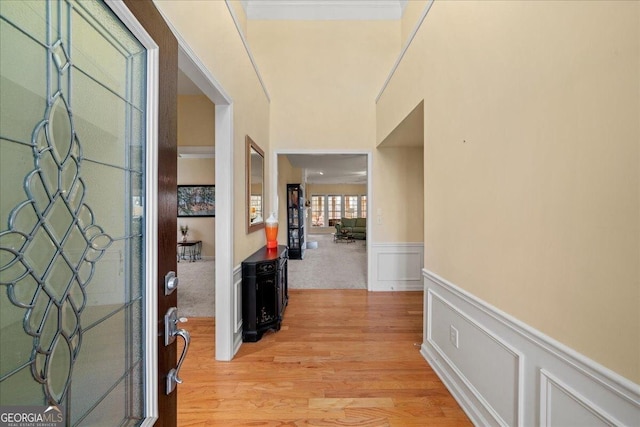 foyer entrance featuring light wood-style floors, wainscoting, and a decorative wall