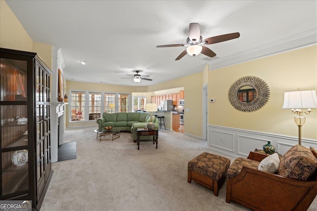 living room with wainscoting, a fireplace, a decorative wall, and light colored carpet