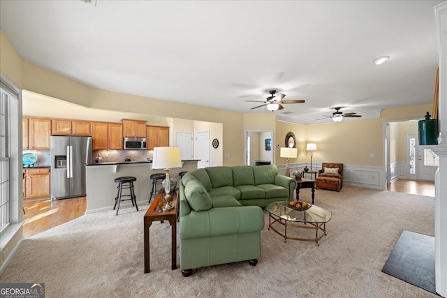 living room featuring a wainscoted wall, a decorative wall, and light colored carpet