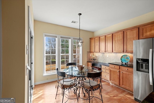 kitchen with tasteful backsplash, decorative light fixtures, stainless steel refrigerator with ice dispenser, and light hardwood / wood-style floors