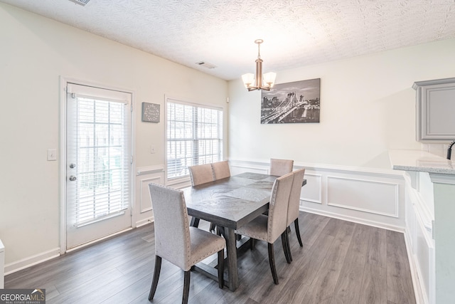 dining room with an inviting chandelier, a textured ceiling, and dark wood-type flooring