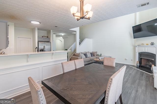 dining area featuring dark hardwood / wood-style floors, a textured ceiling, and a notable chandelier