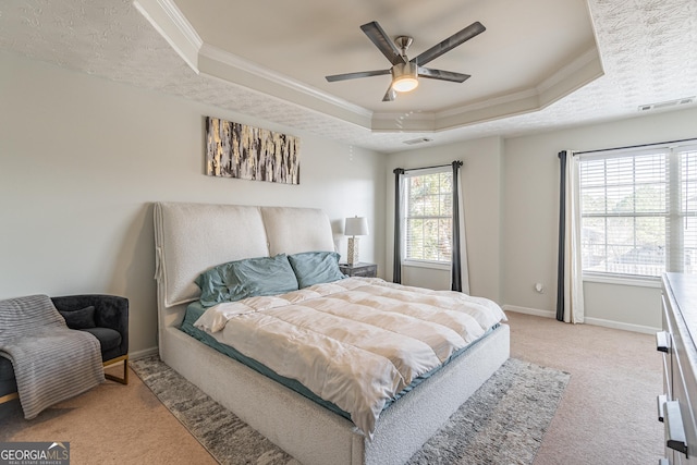 bedroom with a raised ceiling, multiple windows, and ceiling fan