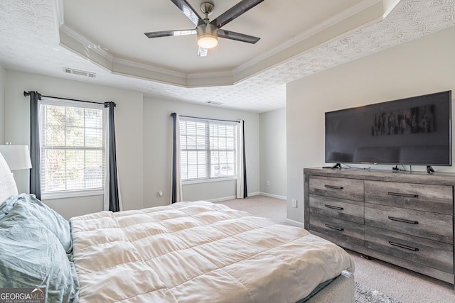 bedroom with ceiling fan, light colored carpet, ornamental molding, and a tray ceiling