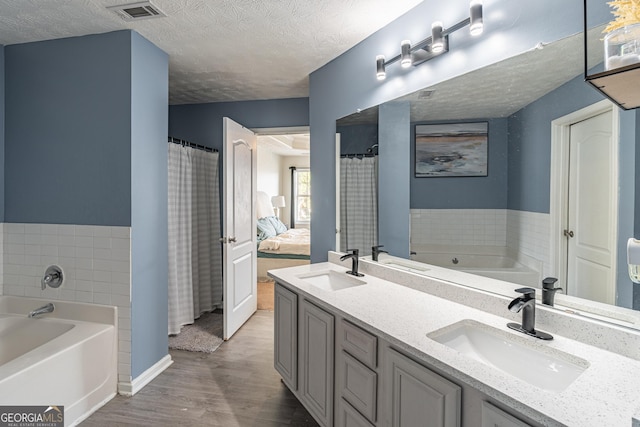 bathroom featuring hardwood / wood-style floors, vanity, a bathing tub, and a textured ceiling