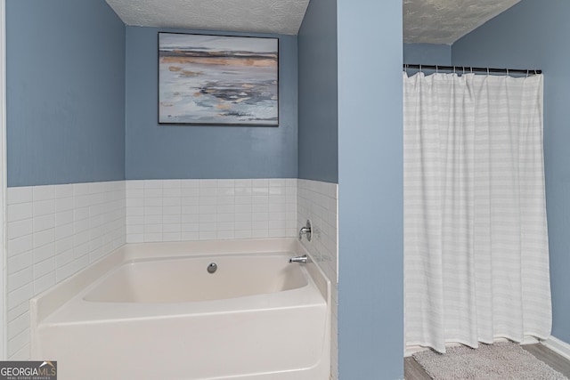 bathroom with a textured ceiling and a bathtub