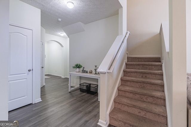 staircase featuring wood-type flooring and a textured ceiling