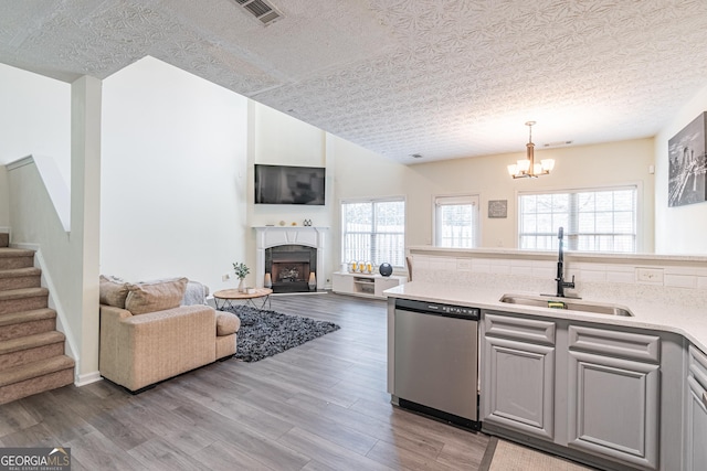 kitchen with dishwasher, sink, an inviting chandelier, decorative light fixtures, and light wood-type flooring