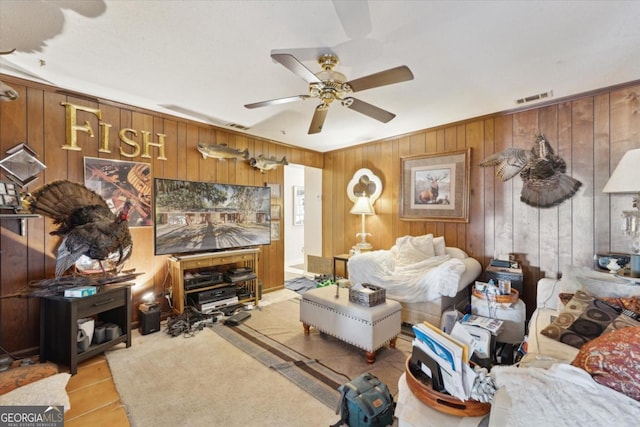 tiled living room with ceiling fan and wood walls