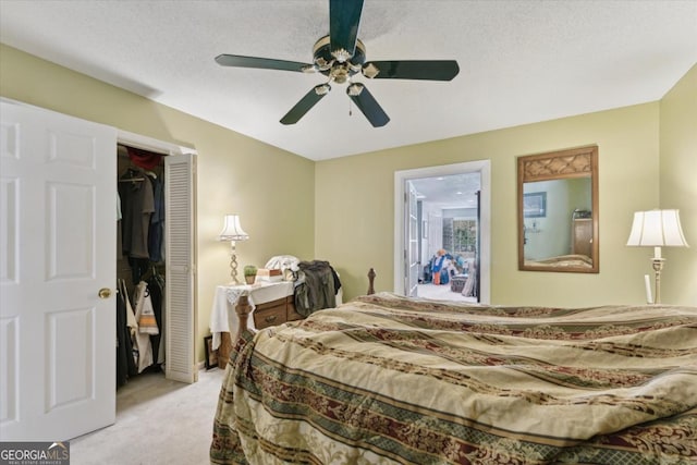 carpeted bedroom featuring ceiling fan, a closet, ensuite bathroom, and a textured ceiling