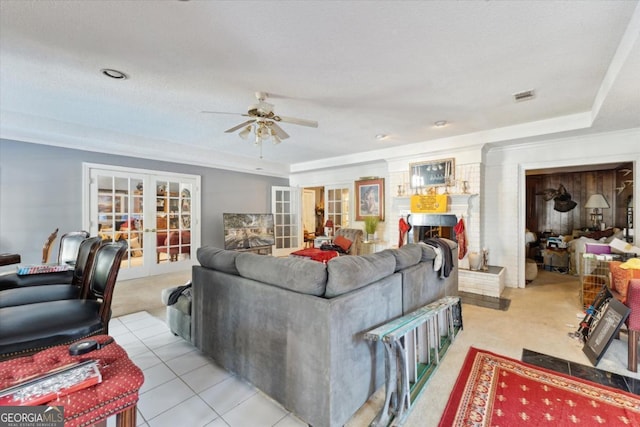 living room with ceiling fan, french doors, a brick fireplace, a textured ceiling, and light tile patterned flooring