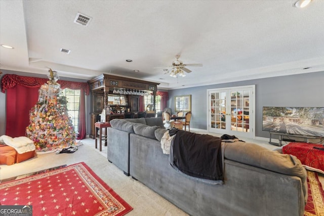 living room with french doors, a textured ceiling, a tray ceiling, and ceiling fan