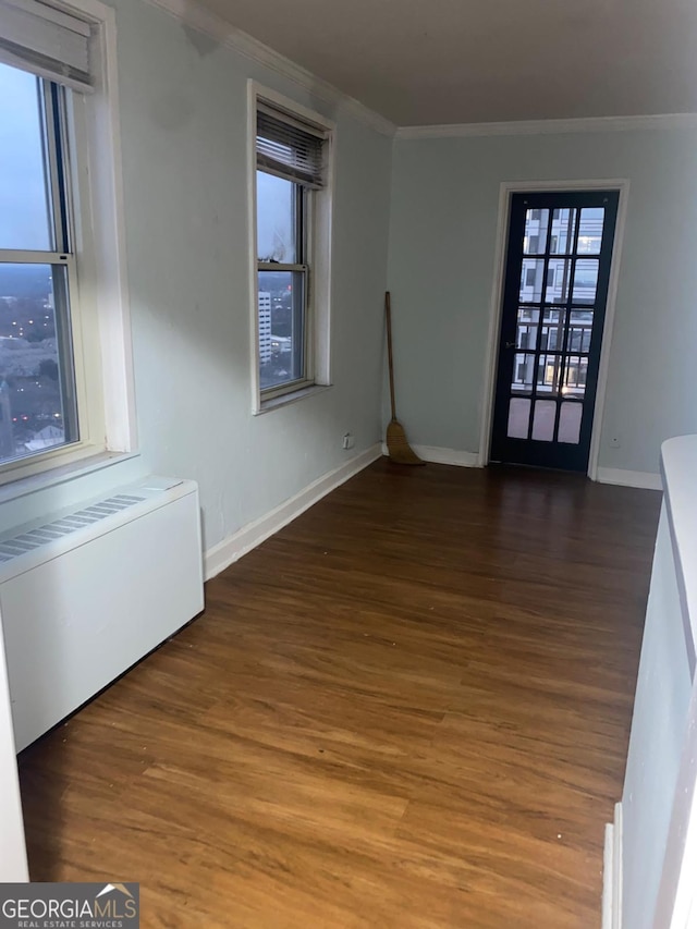 spare room featuring dark wood-type flooring, radiator, and ornamental molding