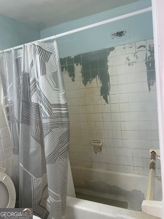 bathroom with shower / bath combination with curtain and toilet