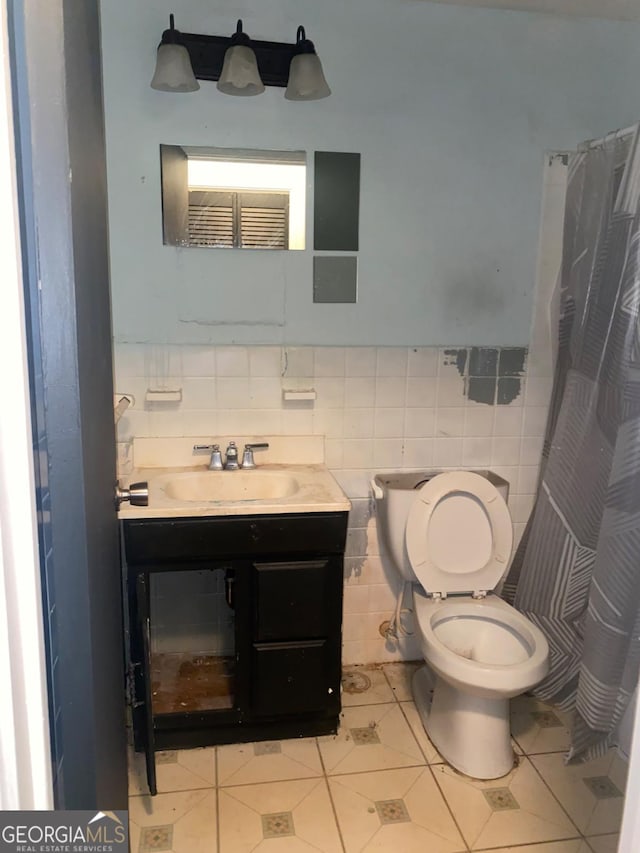 bathroom with tile patterned floors, vanity, toilet, and tile walls