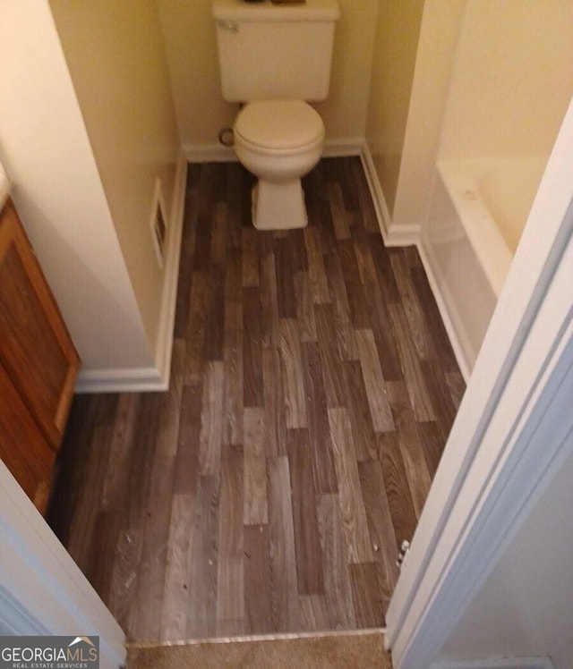 bathroom with hardwood / wood-style floors, a bathtub, and toilet