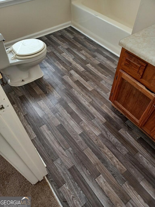 bathroom with a bathtub, toilet, vanity, and hardwood / wood-style flooring