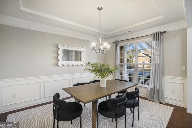 dining room featuring a chandelier, dark hardwood / wood-style floors, a raised ceiling, and crown molding