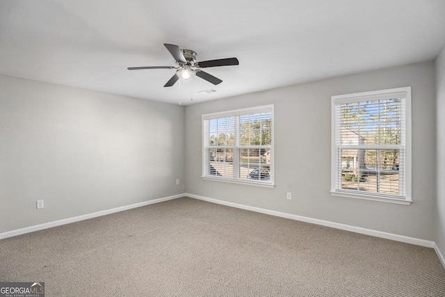 carpeted empty room with a wealth of natural light and ceiling fan