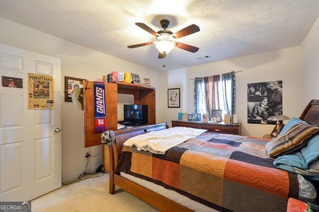 bedroom with ceiling fan, light colored carpet, and a textured ceiling