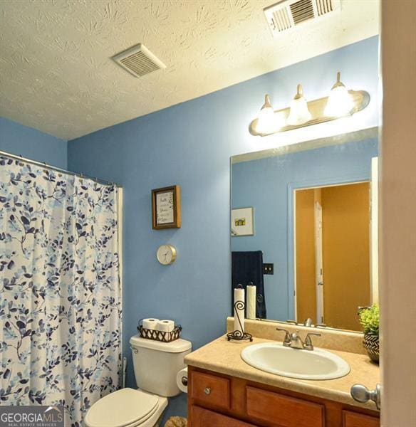 bathroom featuring vanity, curtained shower, toilet, and a textured ceiling