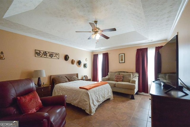 bedroom featuring ceiling fan, a raised ceiling, tile patterned floors, a textured ceiling, and ornamental molding