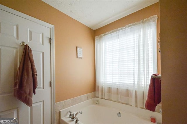 bathroom featuring a bathing tub, a healthy amount of sunlight, and a textured ceiling