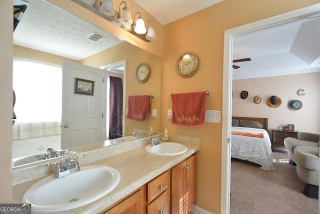 bathroom featuring ceiling fan, tile patterned flooring, vanity, and a textured ceiling