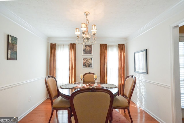 dining space featuring light wood-type flooring, an inviting chandelier, and ornamental molding