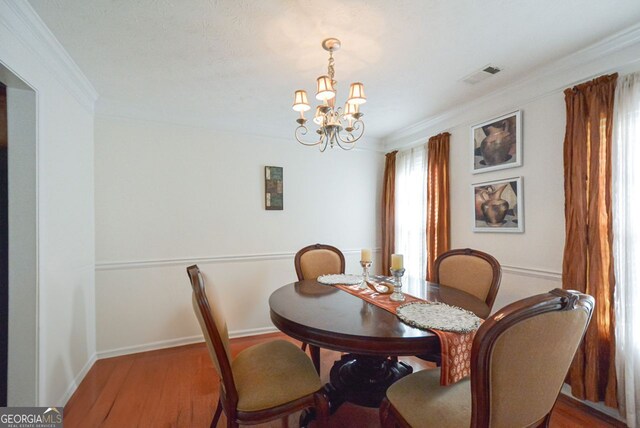 dining area featuring hardwood / wood-style floors, ornamental molding, and a chandelier